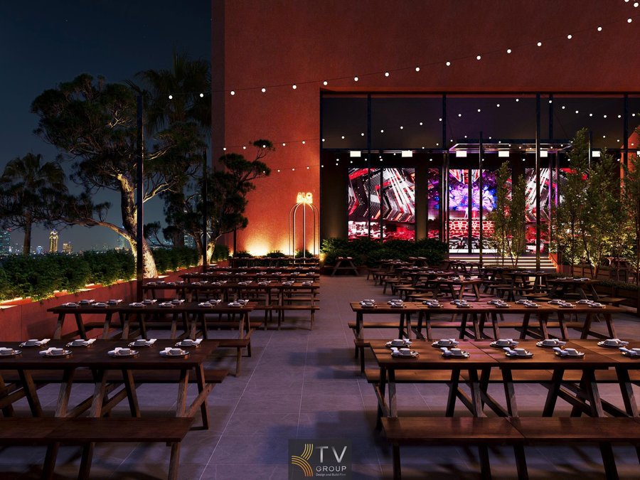 Không gian Beer Garden được thiết kế mở, nổi bật với hệ bàn ghế gỗ dài sắp xếp gọn gàng, phù hợp phục vụ nhóm đông và sự kiện. Ánh sáng dây treo kết hợp đèn hắt tạo cảm giác ấm