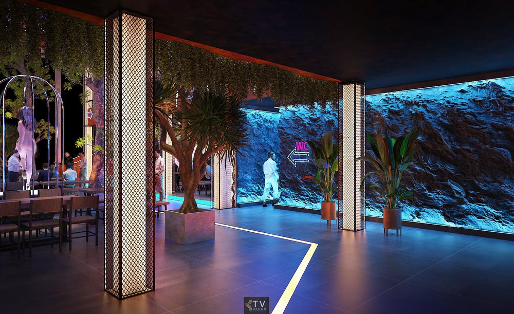 Lối đi Beer Garden ấn tượng với hiệu ứng ánh sáng xanh, tường đá độc đáo và cây xanh trang trí, dẫn vào không gian nightlife sôi động.