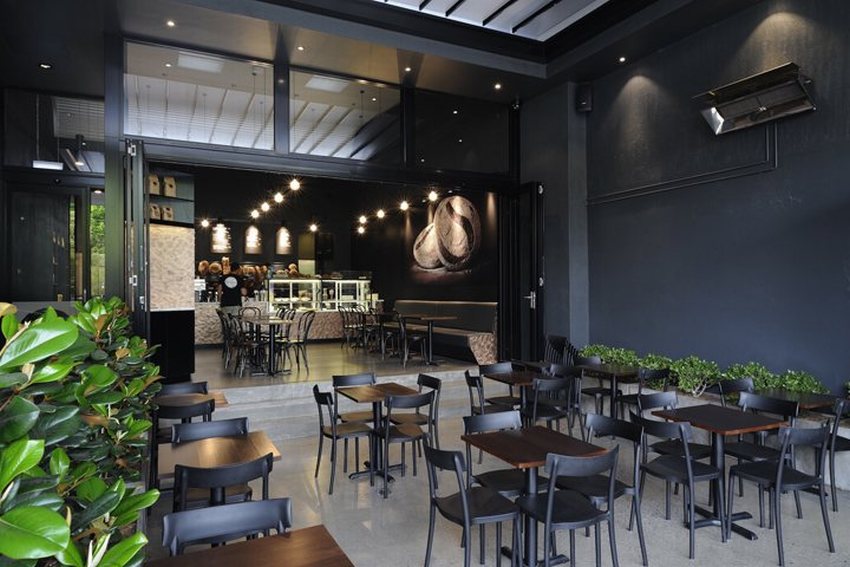 Không gian quán cafe hiện đại với thiết kế mở, nội thất tối giản và tông đen sang trọng, tạo cảm giác thoải mái và gần gũi cho khách hàng.