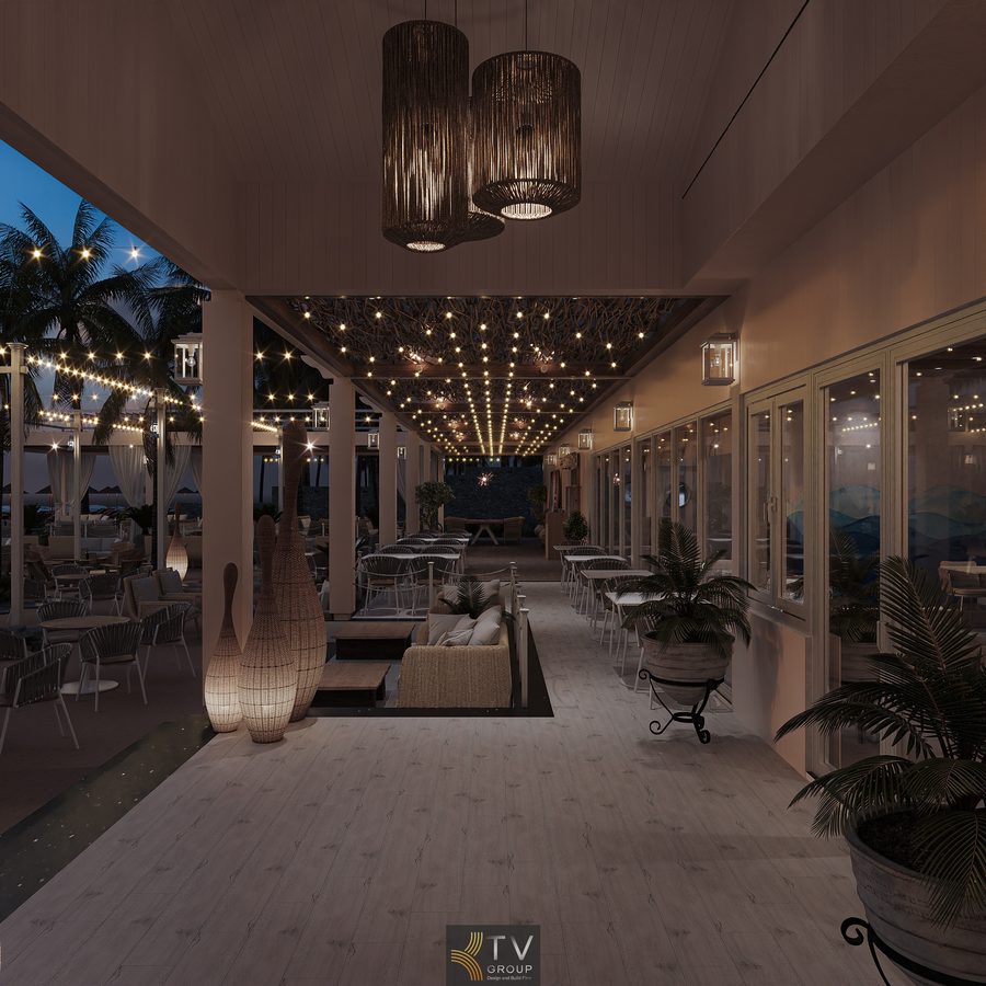 Khu dining cao cấp với bàn ghế wicker, ánh sáng vàng nhẹ và rèm trắng bay, nằm giữa sân vườn dừa hướng thẳng ra biển đêm thơ mộng.