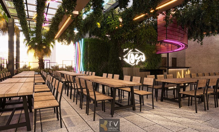 Không gian Beer Garden được thiết kế theo phong cách mở với bàn ghế gỗ mộc mạc, ánh sáng LED điểm nhấn và hệ trần phủ cây xanh tạo cảm giác gần gũi, thư giãn. Khu quầy bar được bố trí nổi bật, mang lại không khí sôi động và hiện đại.