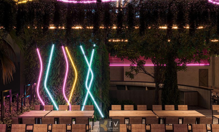 Không gian Beer Garden nổi bật với mảng tường cây xanh kết hợp dải LED uốn lượn đa sắc, tạo hiệu ứng thị giác hiện đại và đầy năng lượng. Khu bàn ngoài trời được bố trí thoáng, mang lại trải nghiệm ẩm thực – giải trí sống động về đêm.