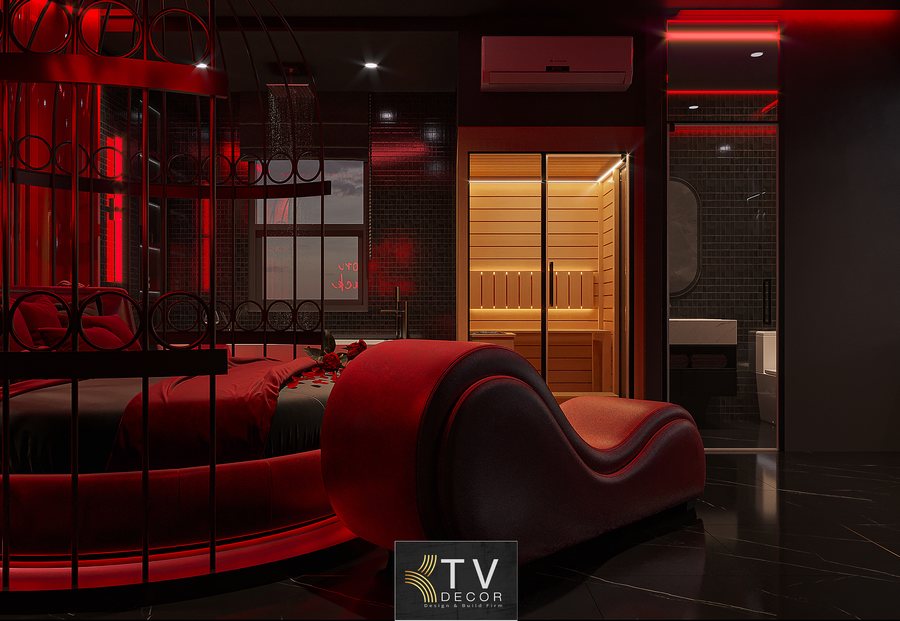 Ghế thư giãn thiết kế cong mềm mại đặt cạnh giường tròn, phối hợp tông đỏ – đen tạo nên không gian nghỉ dưỡng độc đáo trong phòng khách sạn. 