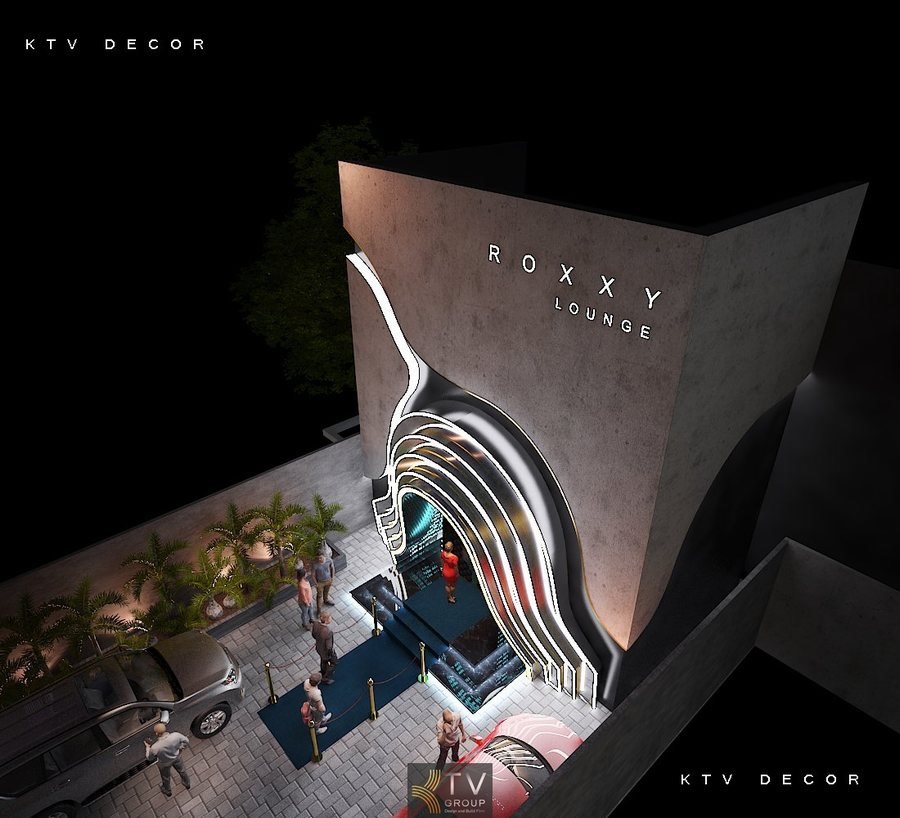Alt: lối vào lounge với thảm đỏ và hàng rào phân luồng  Alt: cấu trúc đường cong đa lớp ánh sáng tại mặt tiền ROXXY  Alt: khách bước vào lounge qua cổng ánh sáng  Alt: cây xanh trang trí dọc lối vào bên trái