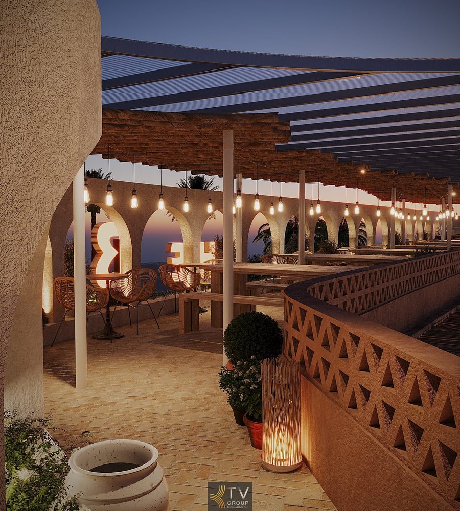 Khu vực ăn uống Beer Garden ngoài trời. Ghế băng dài gỗ thô, tường phong cách Địa Trung Hải. 