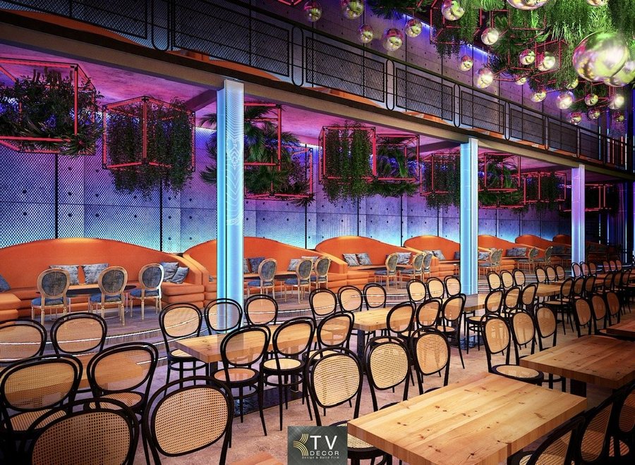 Không gian Beer Garden nổi bật với dãy sofa cam bo cong sang trọng, bàn ghế gỗ mộc ấm áp và hệ cây xanh treo cao tạo cảm giác thoáng đãng. Ánh sáng neon tím–xanh kết hợp trần gương cầu mang đến một bầu không khí sôi động, thời thượng và đầy chất giải trí. 